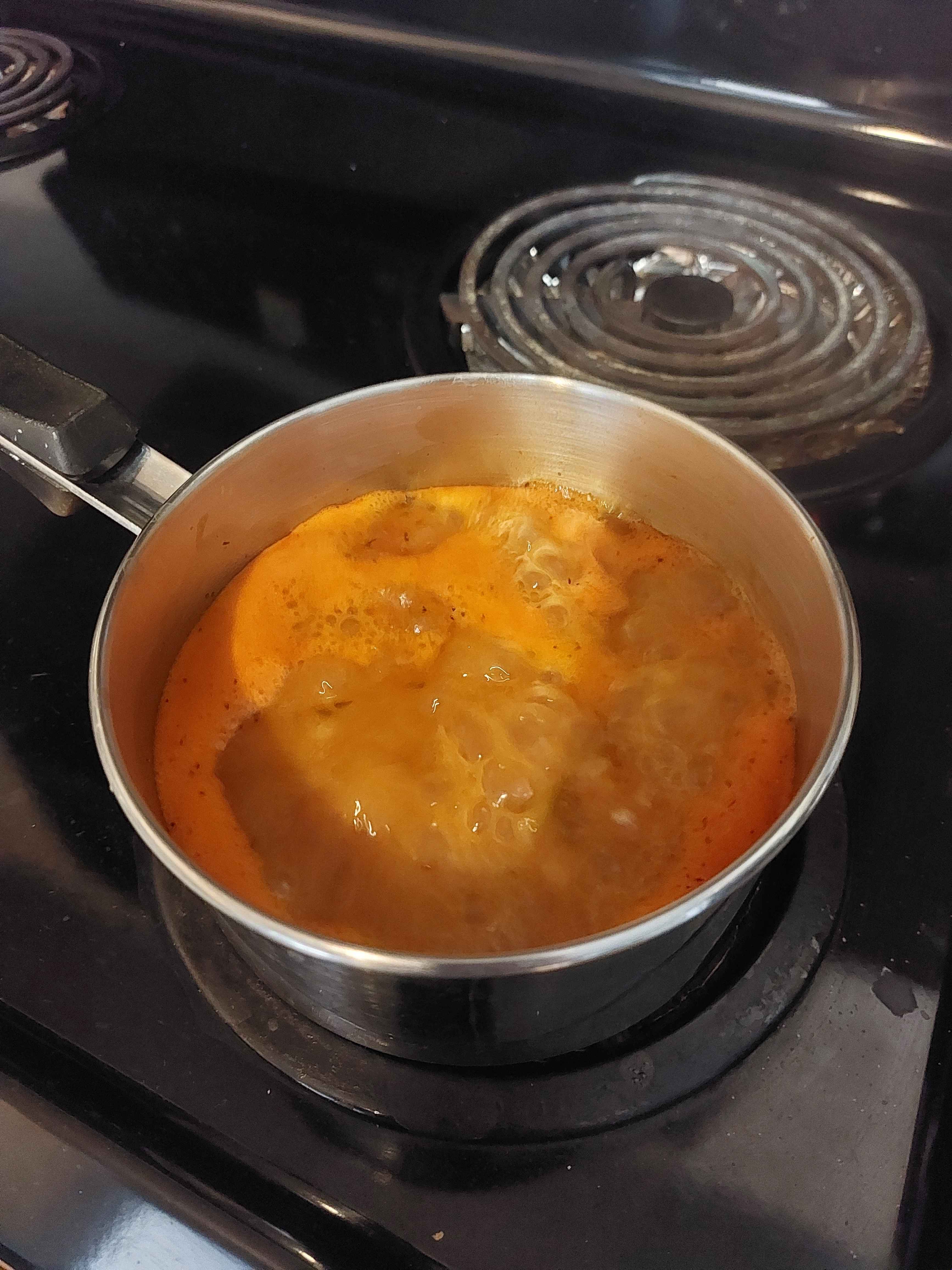 Orange Chicken Gumbo in a silver pot on a black stove boiling